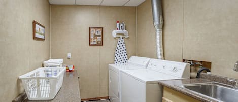 Un lavadero pequeño con lavadora, secadora y lavabo.