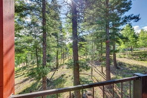 A forested area with tall trees and a wooden deck. - Expansive Angel Fire Home w/ Indoor Hot Tub! (Angel Fire)