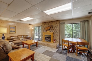 A living room with a fireplace, a sofa set, a coffee table, and a dining table with chairs. - Expansive Angel Fire Home w/ Indoor Hot Tub! (Angel Fire)
