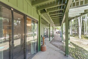 A covered walkway with a concrete floor, metal railings, and a view of a forested area. - Expansive Angel Fire Home w/ Indoor Hot Tub! (Angel Fire)