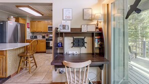 Una cocina con armarios de madera, un refrigerador, un microondas y un comedor con mesa y sillas.