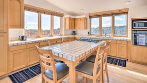 Una cocina moderna con armarios de madera, una isla con azulejos y grandes ventanales con vistas a la ciudad.