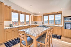 Een moderne keuken met houten kastjes, een betegeld eiland en grote ramen met uitzicht op de stad.