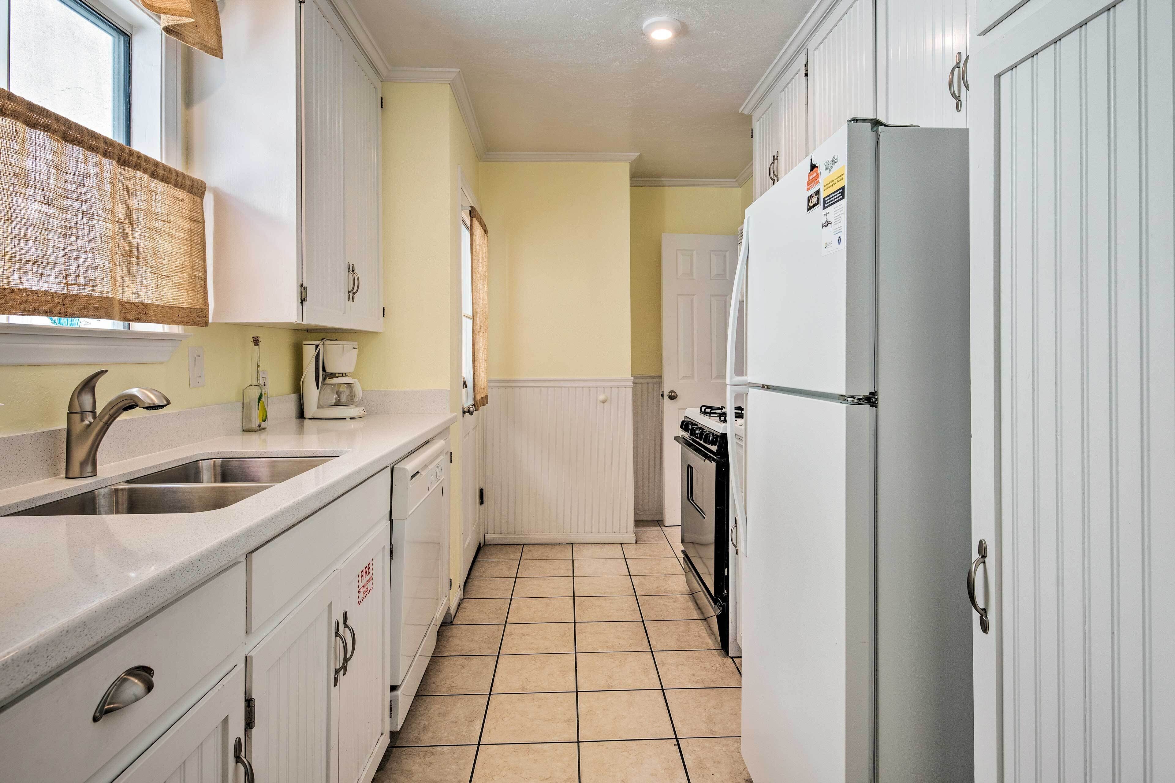 A compact kitchen with white cabinets, a stainless steel sink, and a white refrigerator.