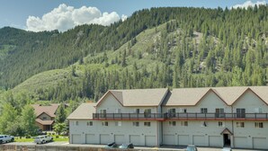 Edificio de dos pisos con balcón, rodeado por un paisaje montañoso y boscoso.