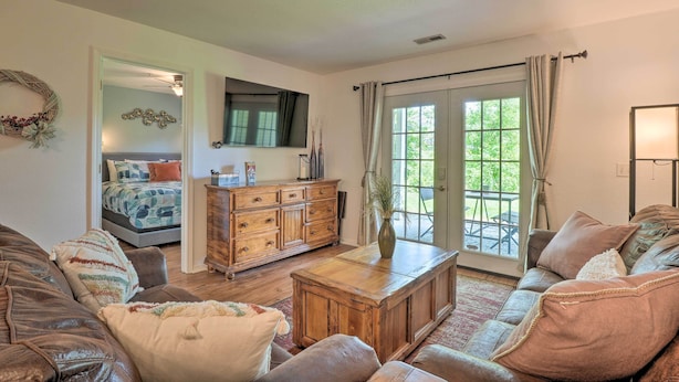Un salon avec un canapé, une table basse, un meuble en bois et un téléviseur fixé au mur.