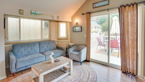 A living room with a sofa, armchair, coffee table, and a large window with blinds. - Tropical Island Escape w/ Deck, Walk to Avalon Bay (Avalon)