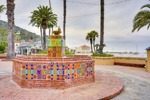 A colorful tiled fountain with a circular brick base, surrounded by palm trees and a coastal backdrop. - Tropical Island Escape w/ Deck, Walk to Avalon Bay (Avalon)