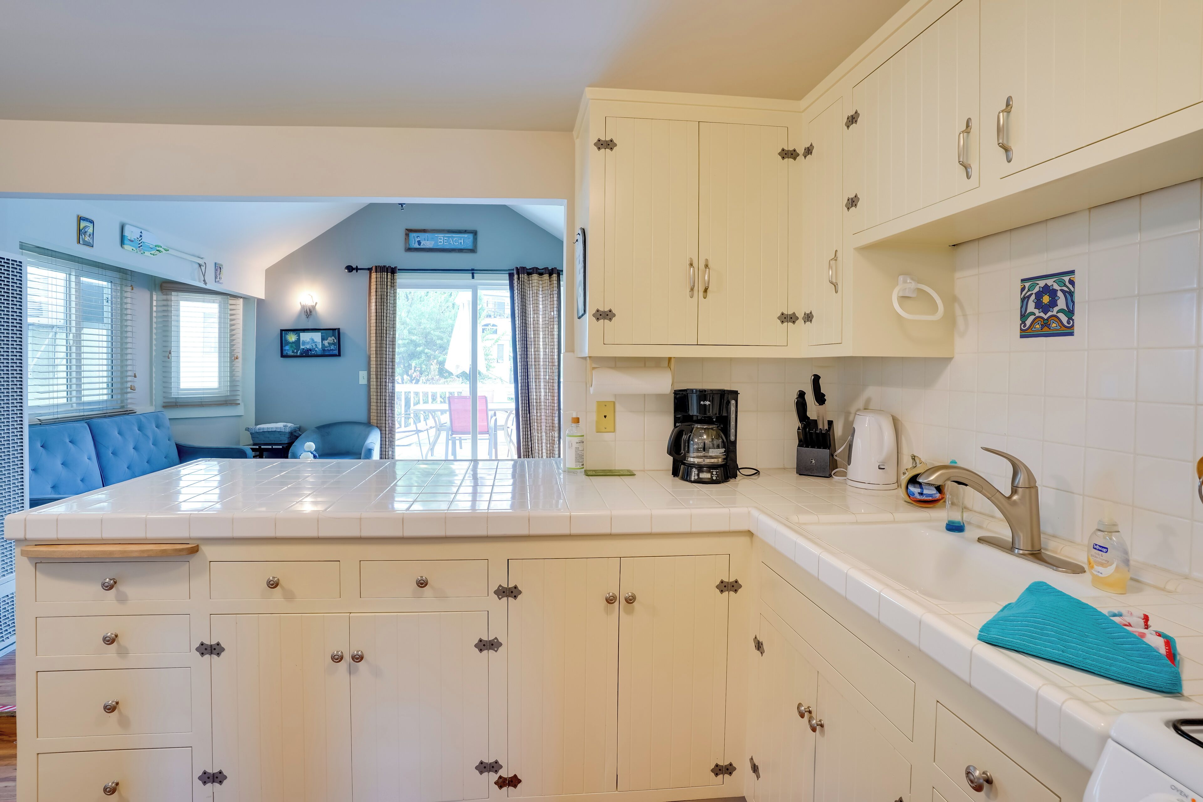 A kitchen with white cabinets, a coffee maker, and a sink.