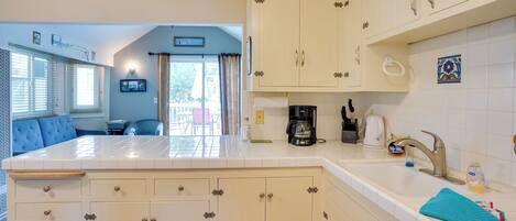 A kitchen with white cabinets, a coffee maker, and a sink.