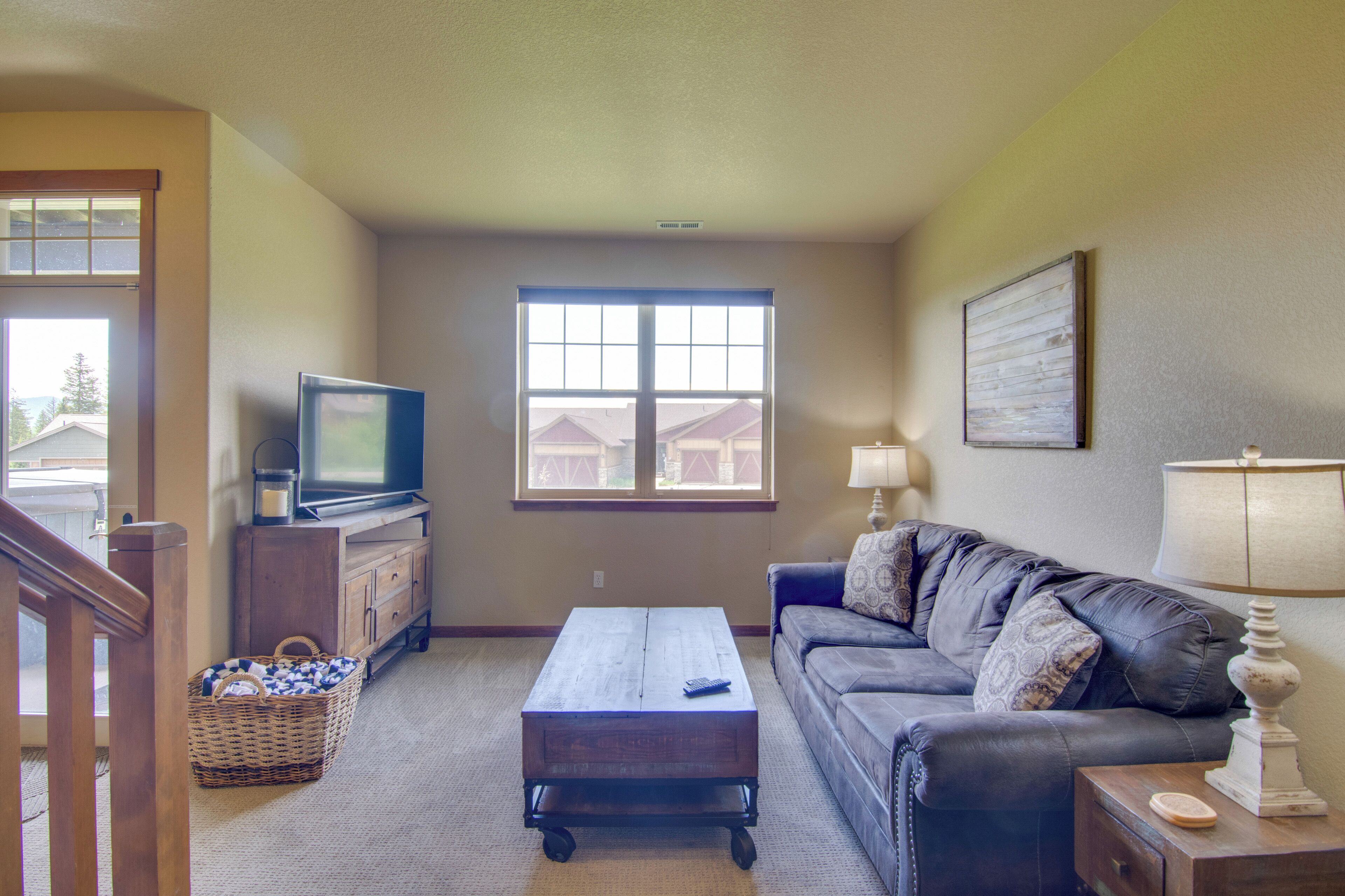 A living room with a television, a sofa, a coffee table, and a window.