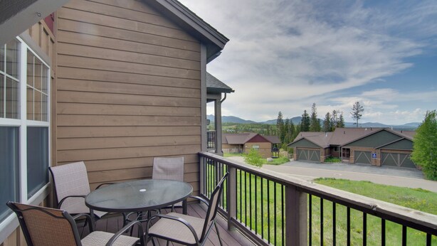 A wooden deck with a round table and four chairs, overlooking a residential area with houses and mountains. - Winter Park Chalet w/ Hot Tub + Free Shuttle! (Fraser)