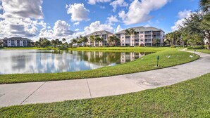 A hotel with a large pond, palm trees, and a clear blue sky. - Jupiter Bay Condo w/ Pool < Half Mile to Beach! (Jupiter)