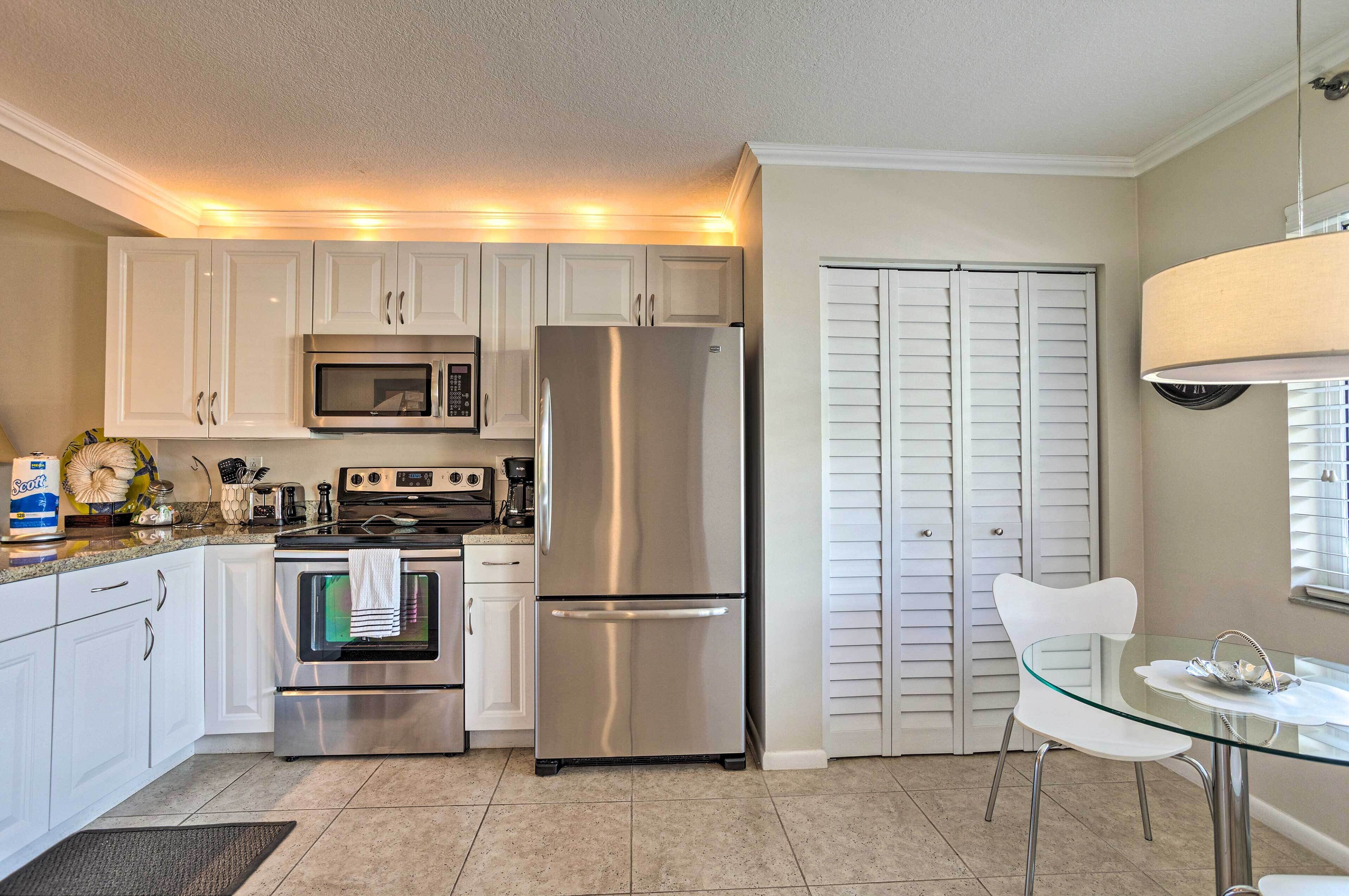 A modern kitchen with stainless steel appliances, a glass dining table, and white cabinetry.