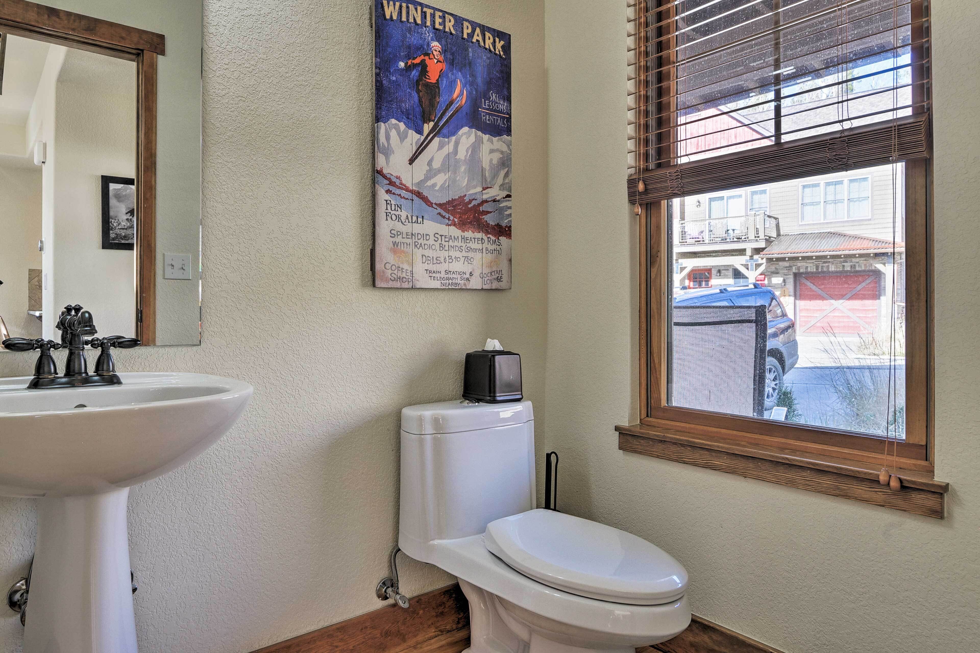A bathroom with a sink, toilet, and a poster advertising ski lessons.