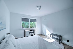 Una camera da letto con un letto, una scrivania, una sedia, una finestra e una porta.