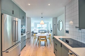 A modern kitchen with a central island, stainless steel appliances, and a dining area with wooden chairs.
