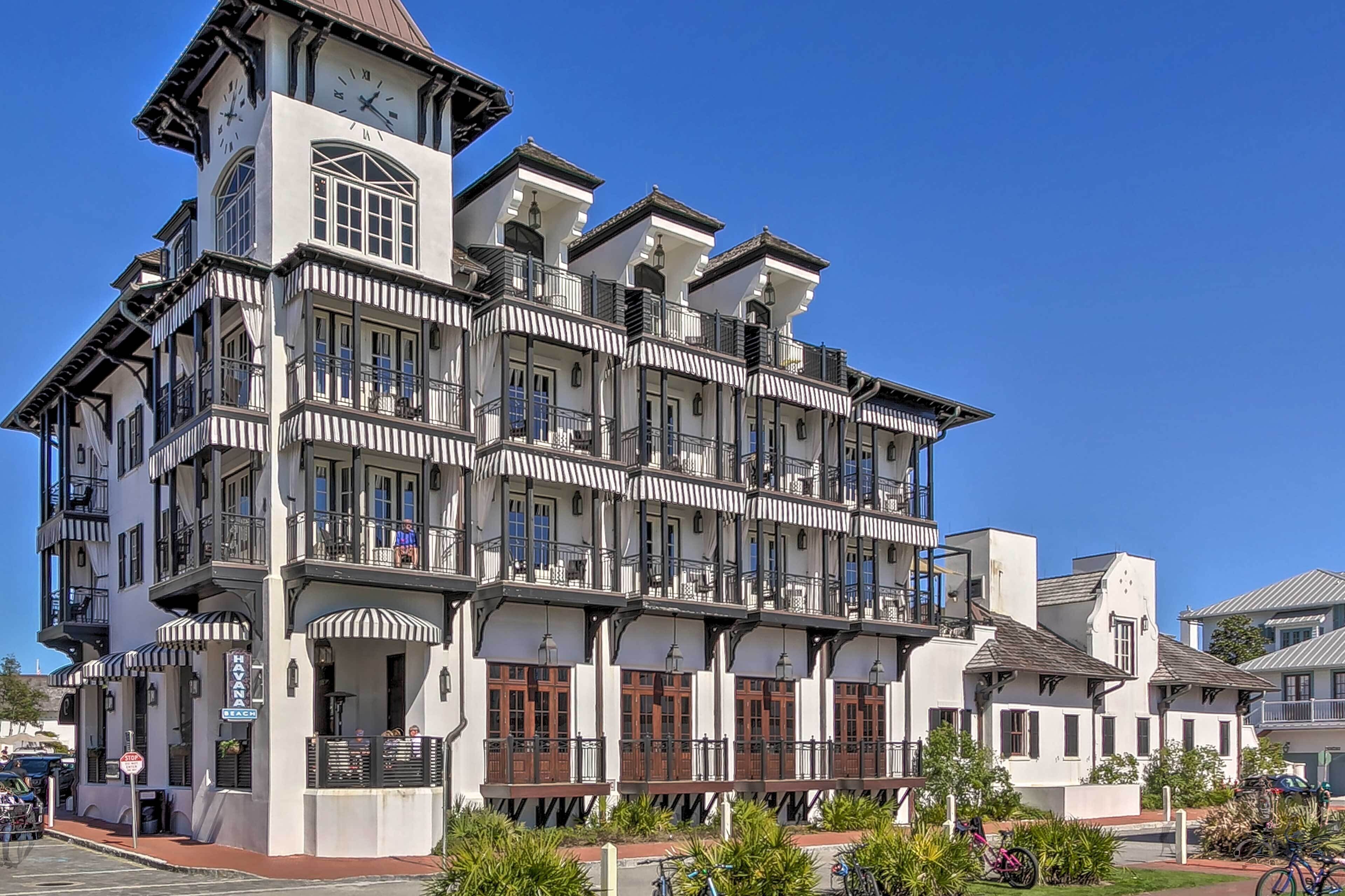 A multi-story building with a clock tower, balconies, and a sign indicating a restaurant.
