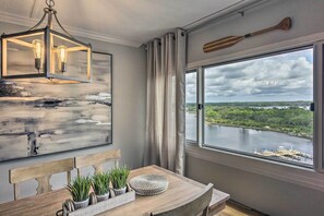 Ein Zimmer mit großem Fenster mit Blick auf einen See, einem Holzespeisetisch mit Pflanzen, einem modernen Kronleuchter und einem Paddel an der Wand.