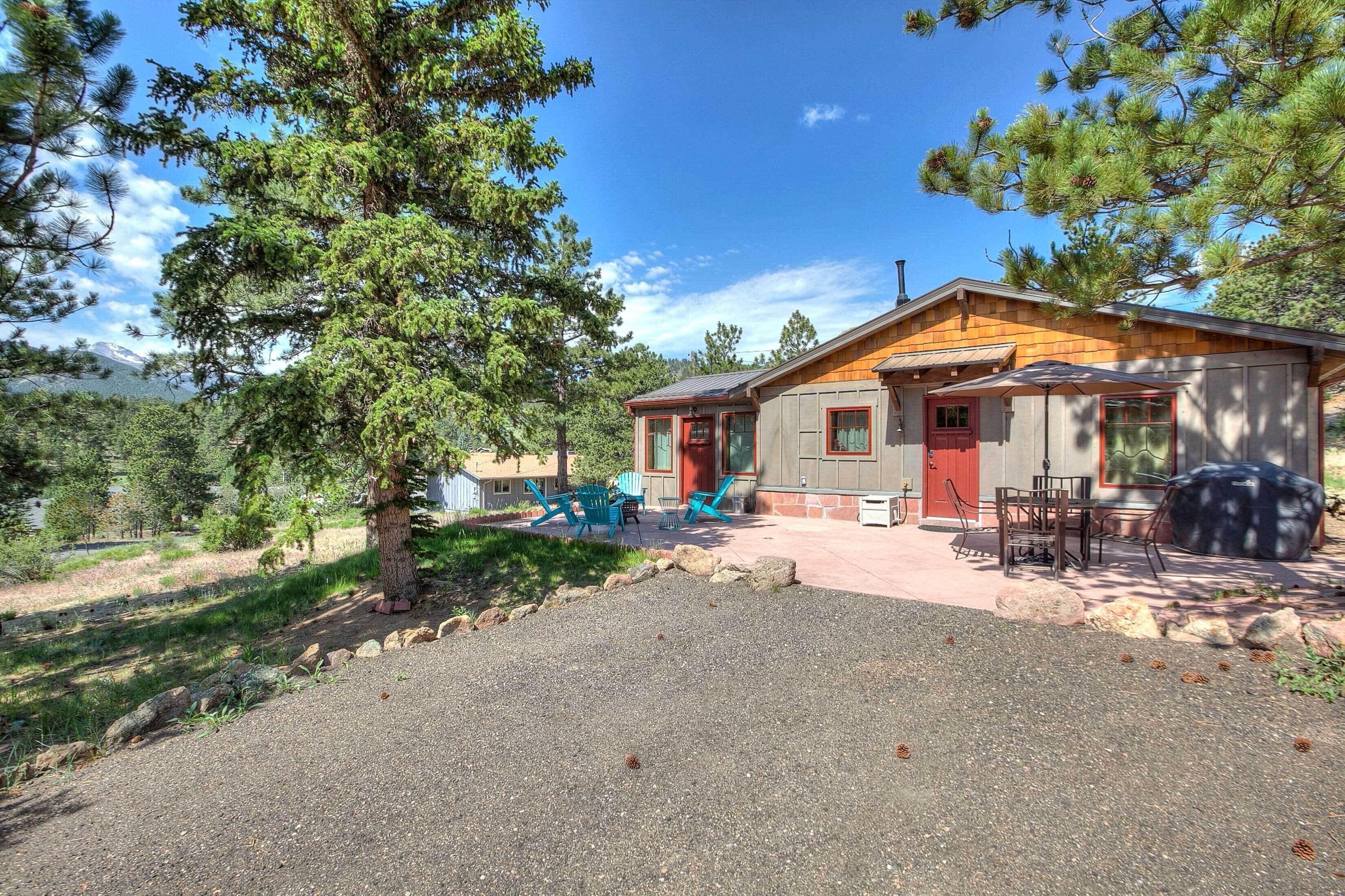 A cabin with a gravel driveway, a red door, and outdoor seating.
