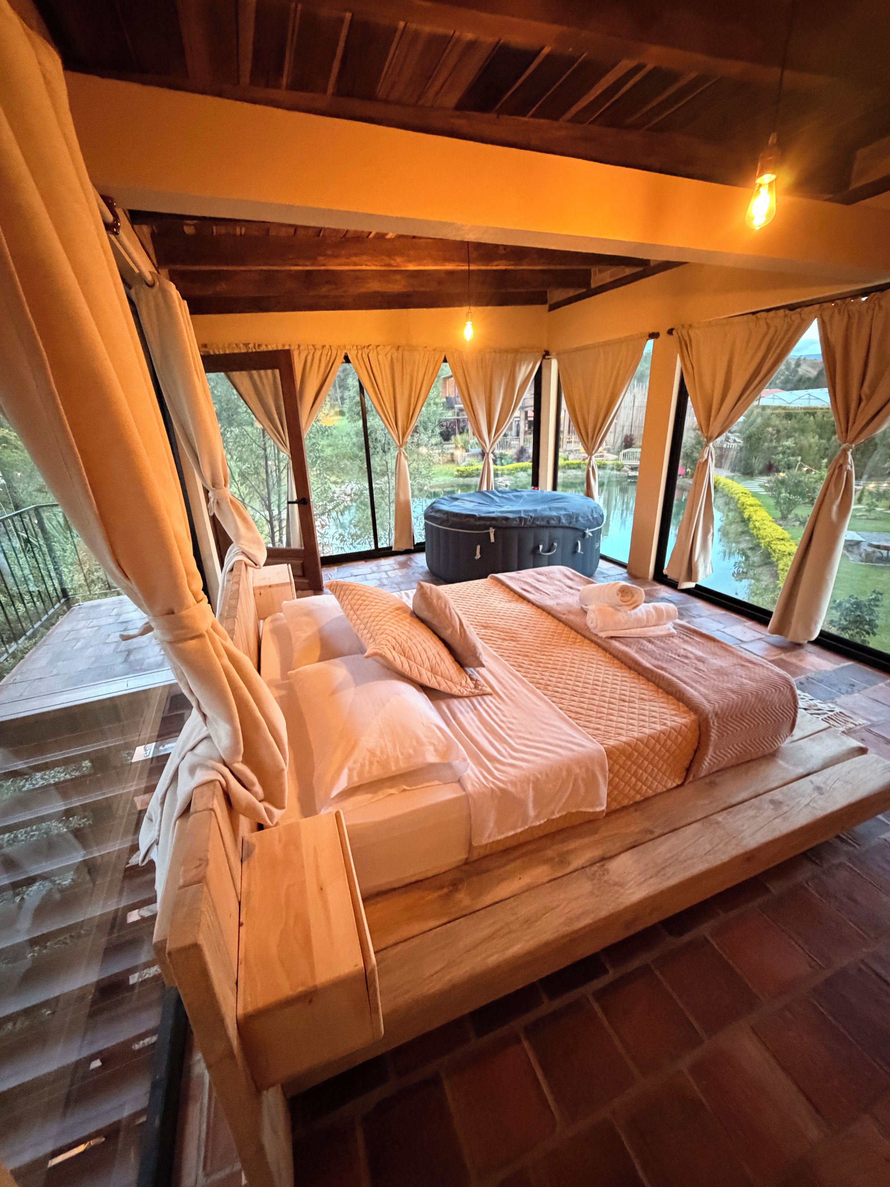 A bed with a canopy, a hot tub, and a view of a garden.