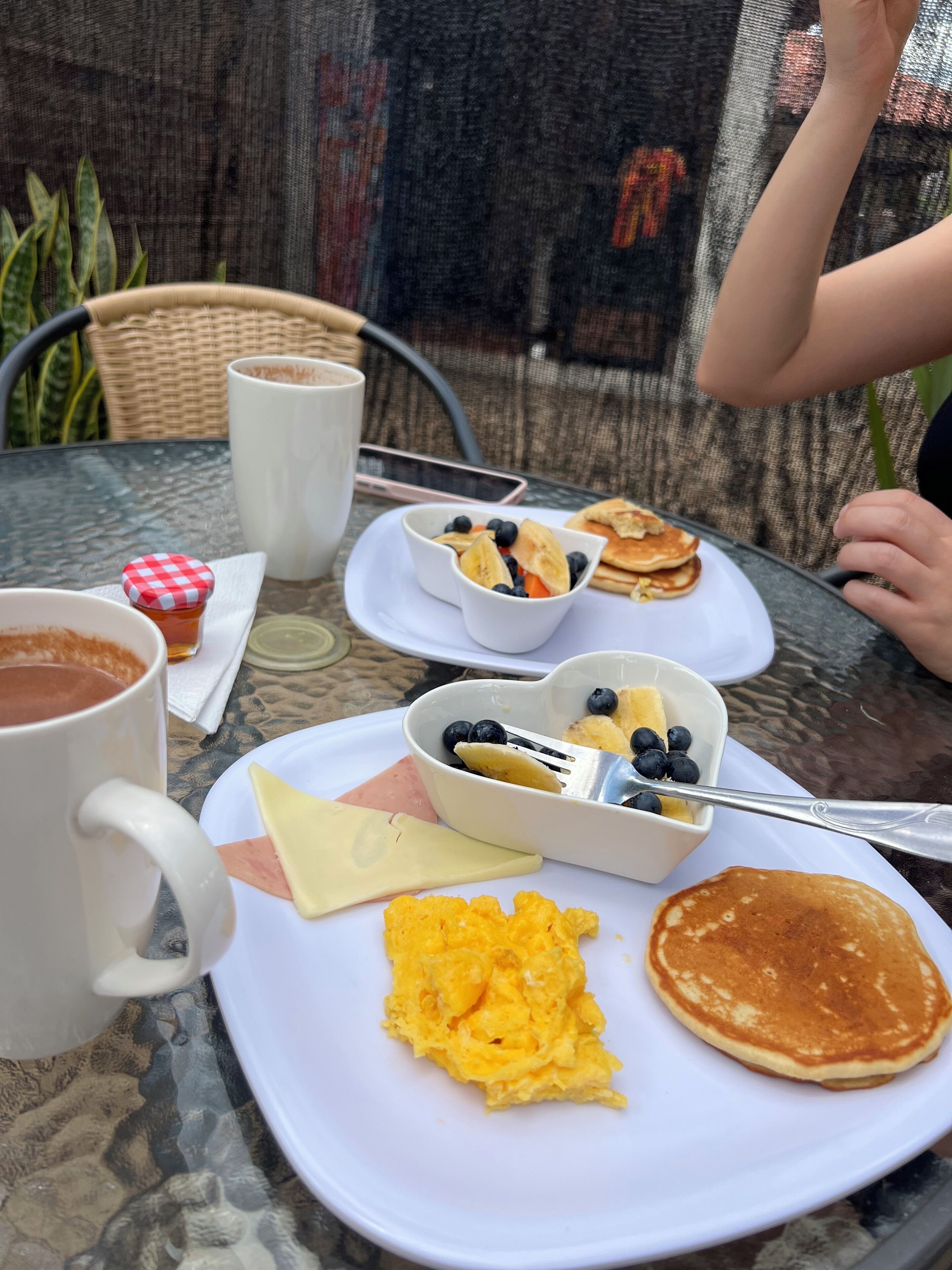 Mesa com ovos mexidos, panquecas e uma caneca de café.