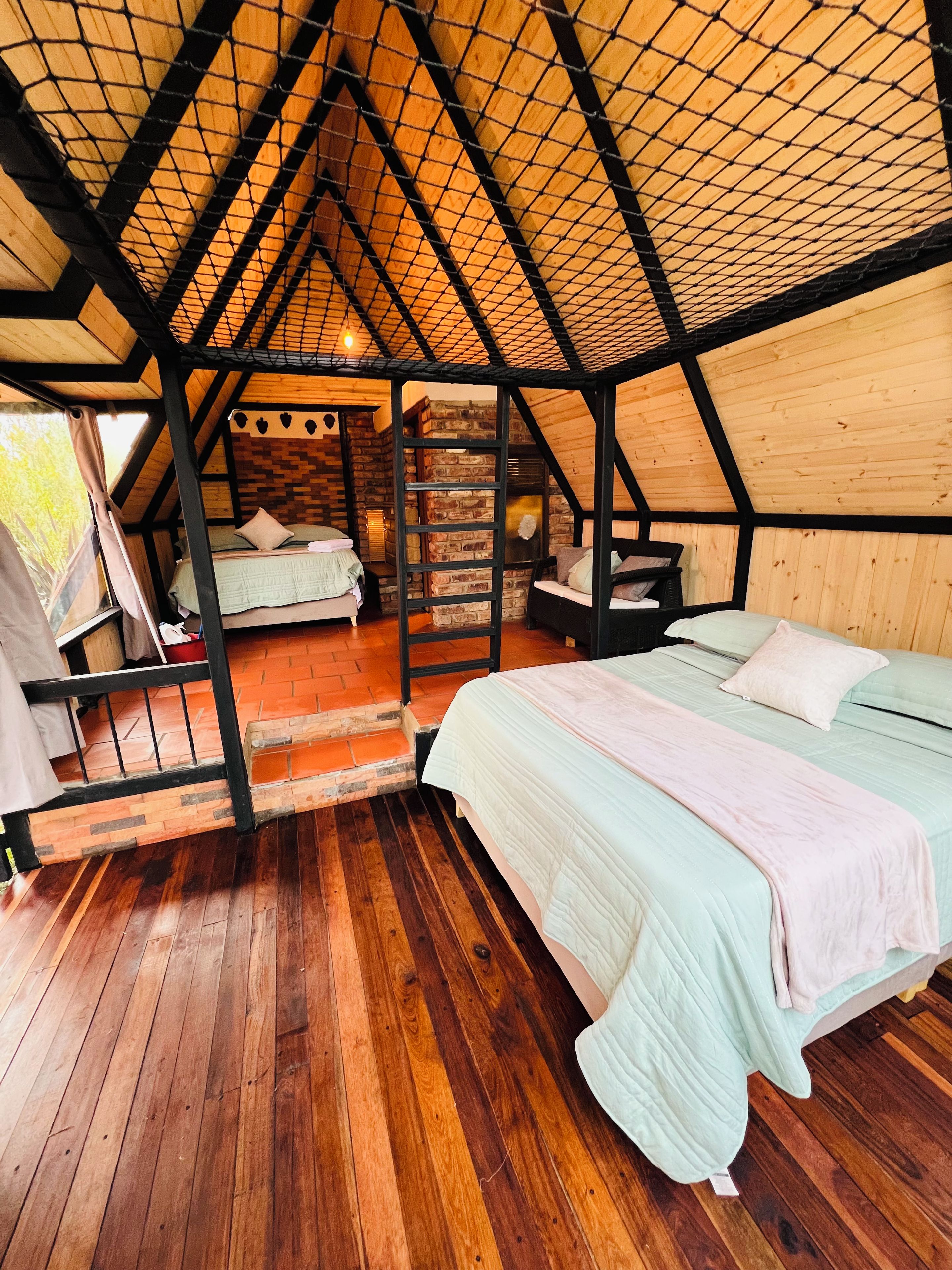 Un dormitorio acogedor en un ático con piso de madera, cama elevadas y pared de ladrillo.