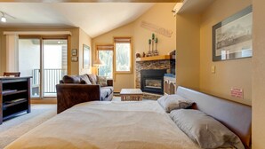 Un dormitorio con una cama grande, chimenea, sofá y escritorio.