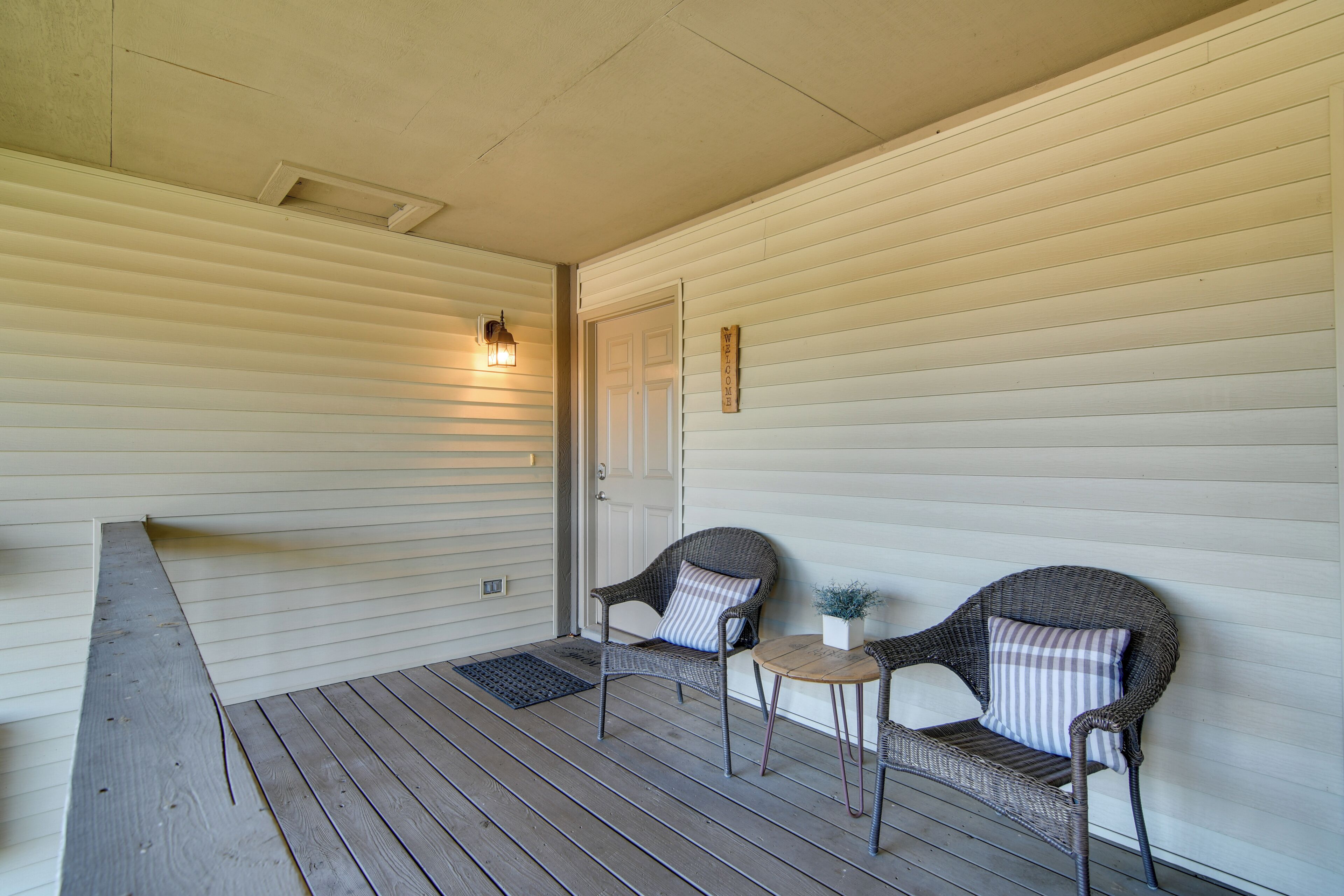 A porch with two wicker chairs, a small table, and a door.