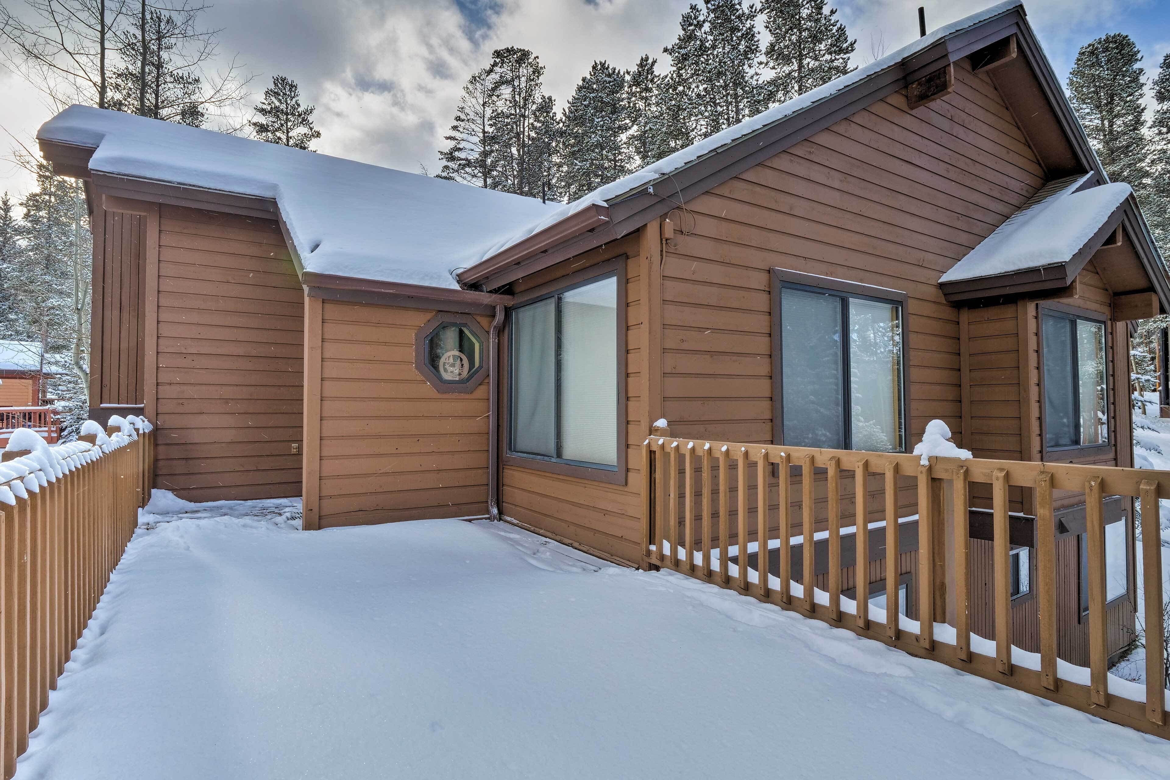 En stuga av trä med en inglasad veranda och ett snötäckt tak.