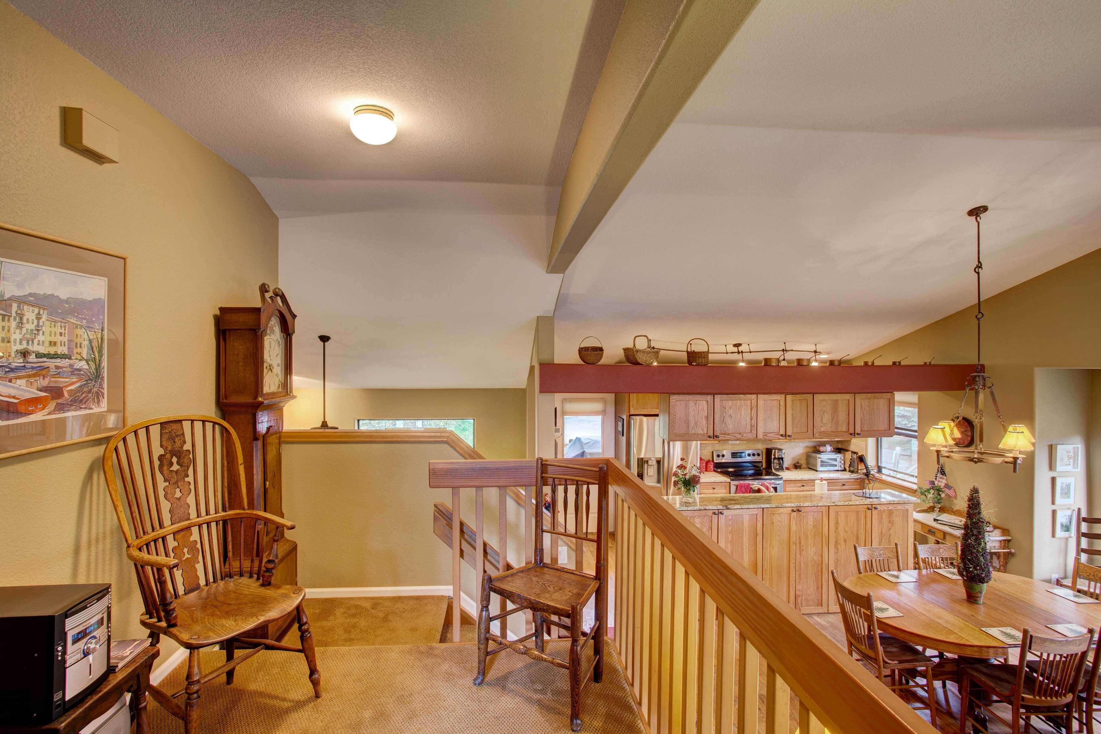 Una cocina espaciosa con armarios de madera, un comedor con mesa y sillas de madera, y una escalera que sube a un nivel superior.