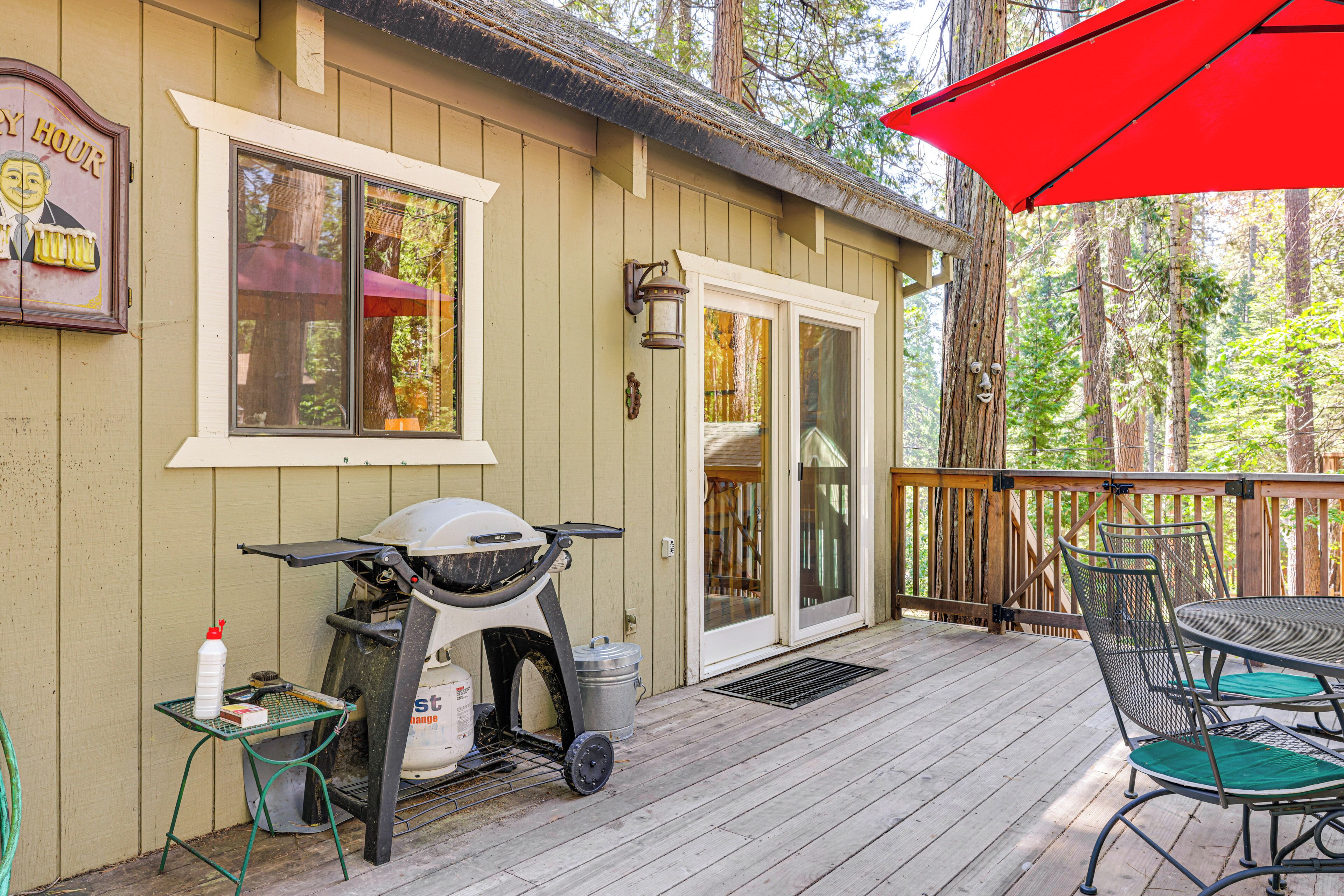 A wooden deck with a patio table and chairs, a scooter, and a red umbrella.