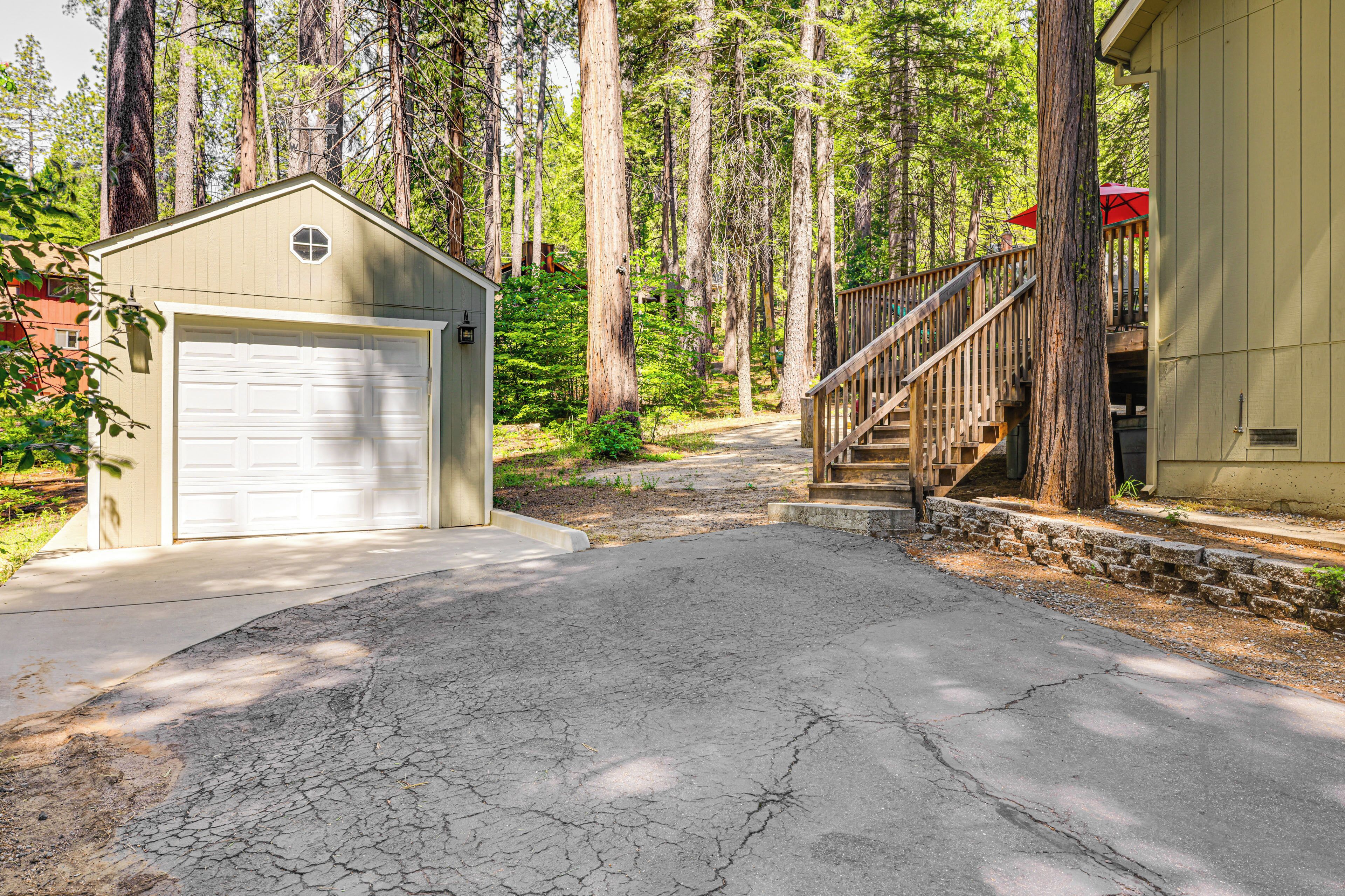 A garage with a white door, a wooden staircase leading to a porch, and a forested area in the background.