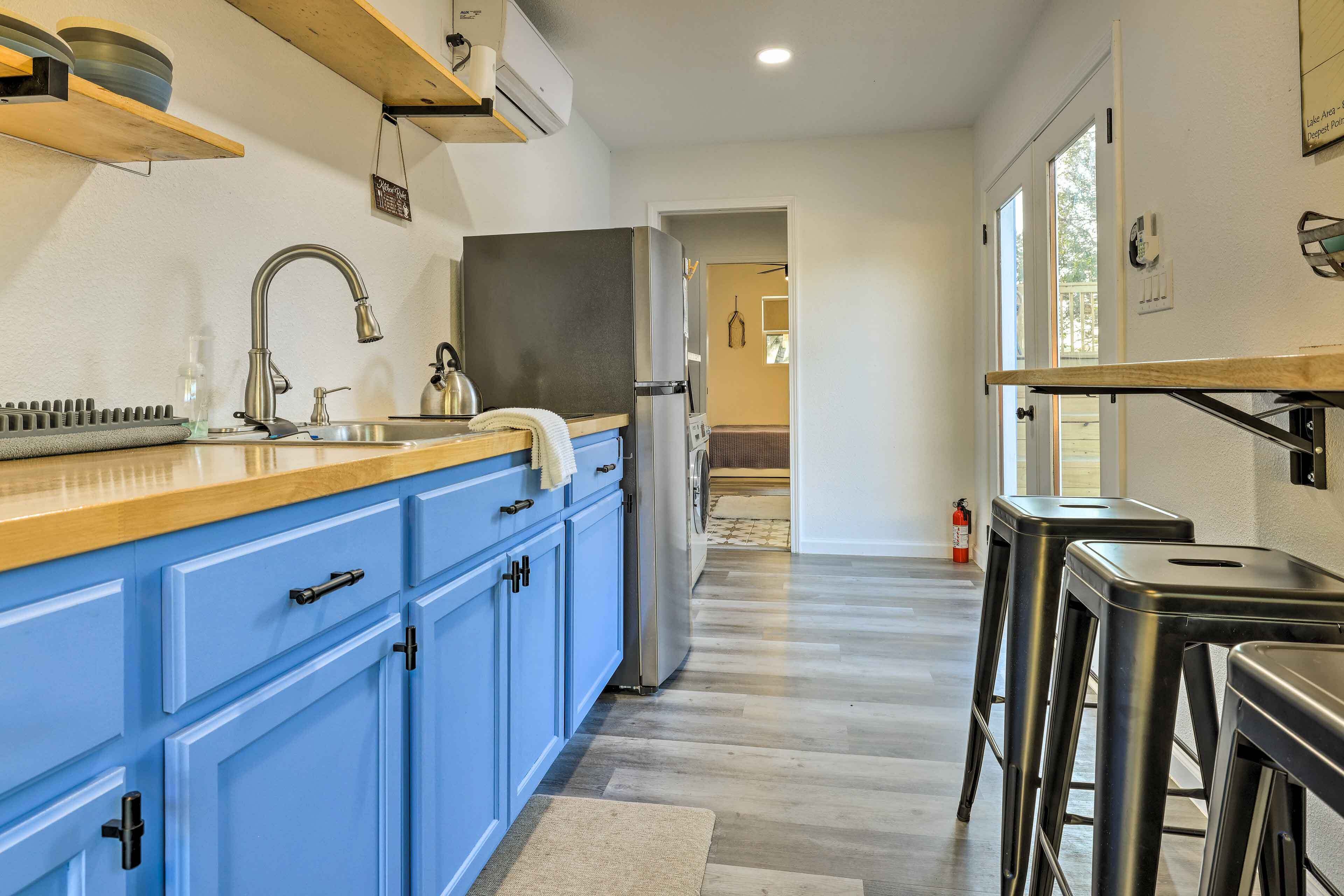 A modern kitchen with blue cabinets, a stainless steel sink, and a built-in oven.
