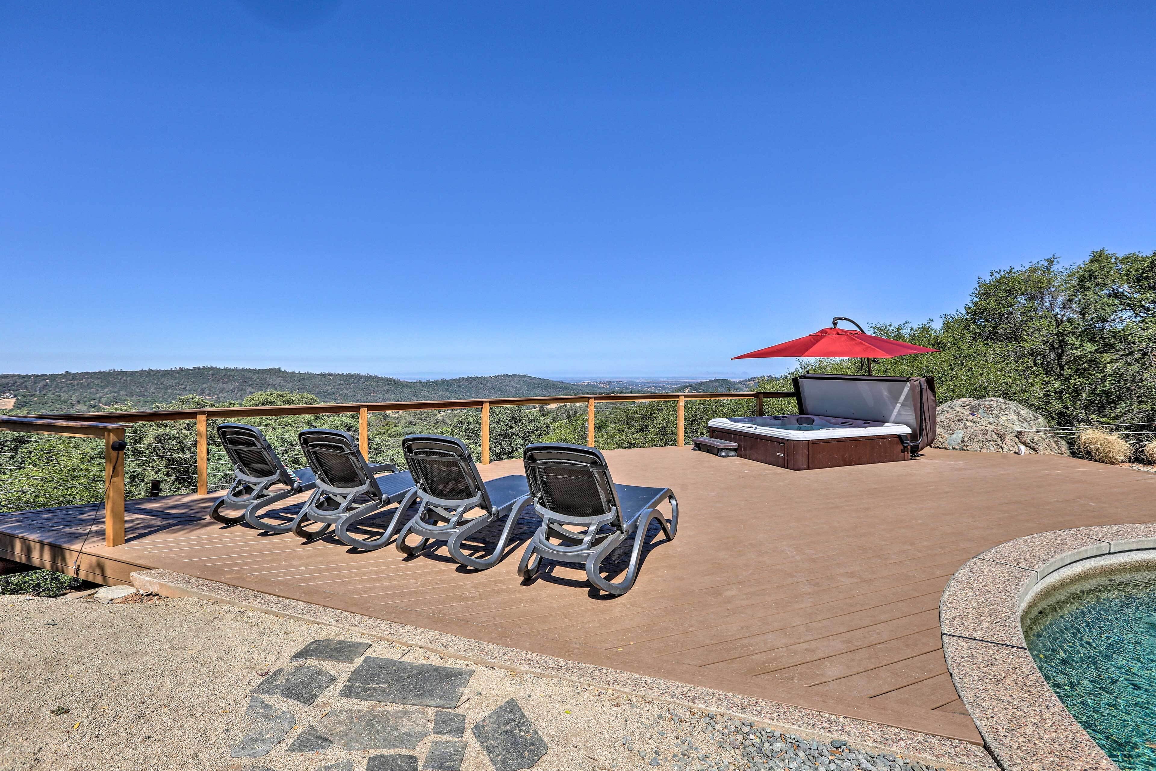 A deck with lounge chairs and a barbecue area, overlooking a scenic landscape.