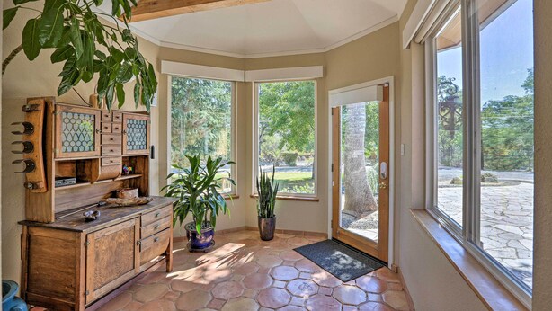 A sunlit room with a wooden cabinet, potted plants, and large windows offering a view of the outdoors. - Luxe Auburn Hideaway w/ Tennis Court & Views! (Auburn)