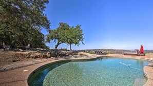 A clear swimming pool with lounge chairs and a red umbrella, surrounded by trees and a clear sky. - Luxe Auburn Hideaway w/ Tennis Court & Views! (Auburn)