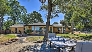 A house with a stone patio, outdoor seating, and a large window overlooking the yard. - Luxe Auburn Hideaway w/ Tennis Court & Views! (Auburn)