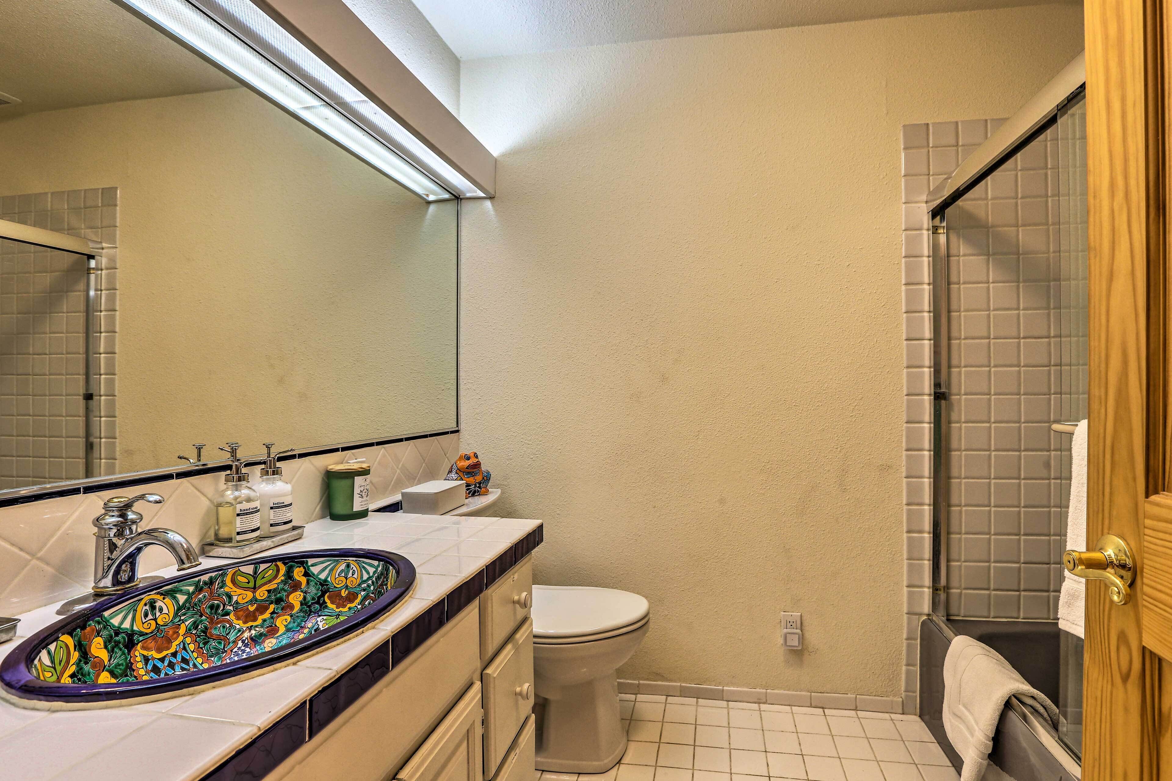 A bathroom with a white sink, a toilet, and a shower area.