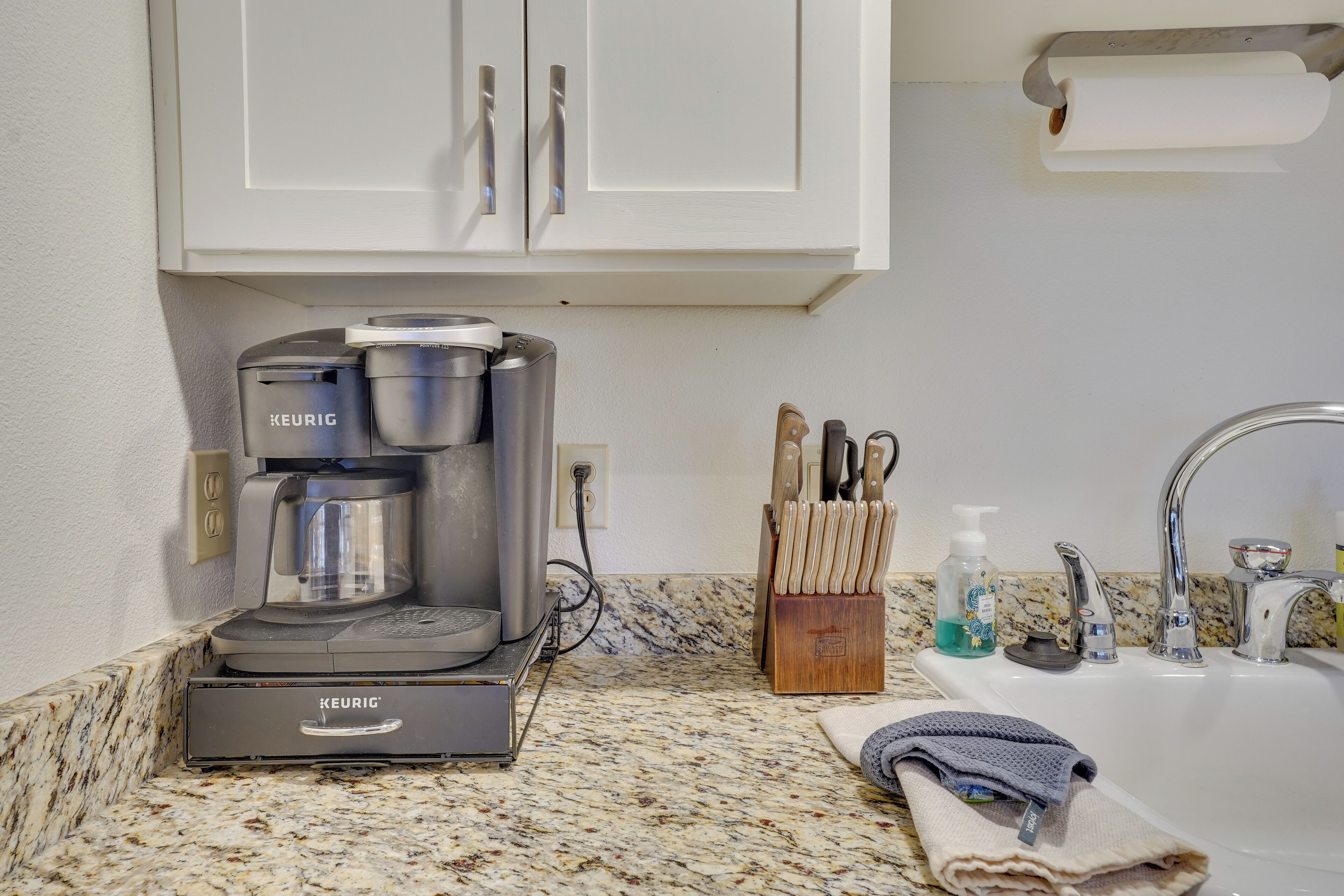 Un angolo cottura con macchina da caffè Keurig, un lavello e un portacoltelli.