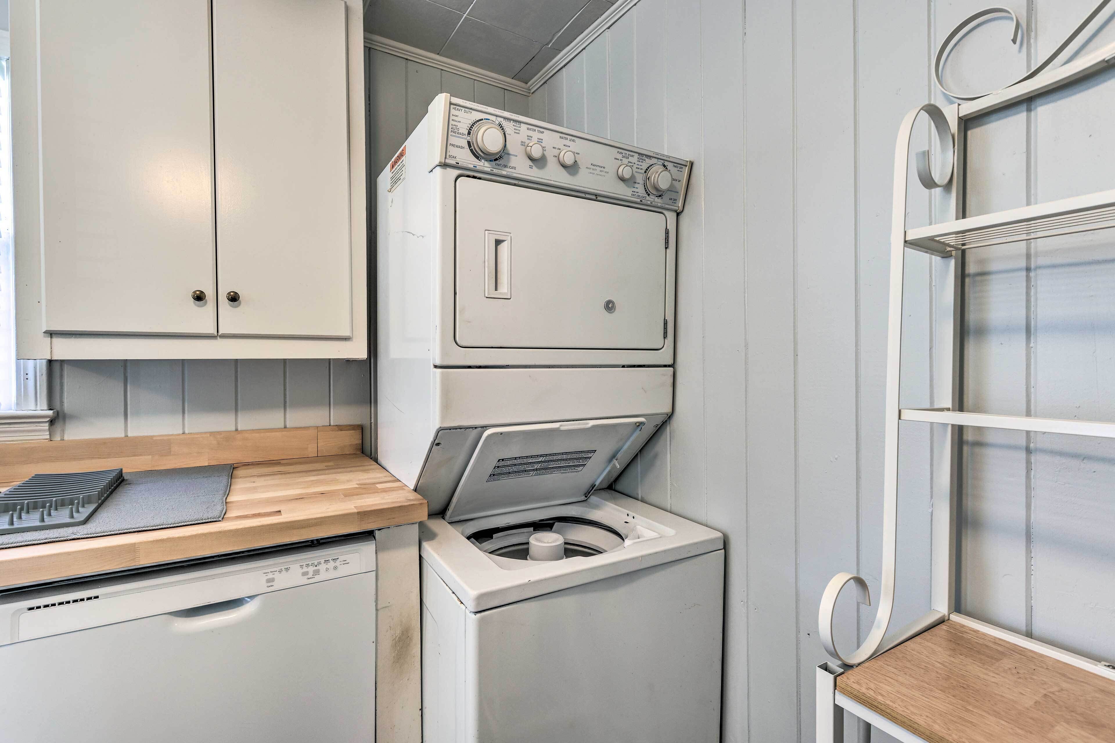 A laundry area with a washing machine and dryer, wooden countertop, and white cabinetry.
