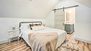 A bedroom with a bed, nightstands, a dresser, and a bathroom with a mirror and sink. - Cozy Spokane Getaway Near Golfing & Skiing! (Spokane)