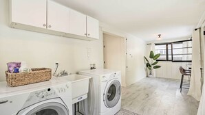 A laundry area with a washing machine and dryer, a wicker basket, and a small sink. - Cozy Spokane Getaway Near Golfing & Skiing! (Spokane)