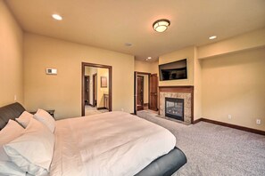 A bedroom with a large bed, a fireplace, and a TV mounted above it. - Spacious Kirkland Home 15 Mi to Dtwn Seattle! (Kirkland)