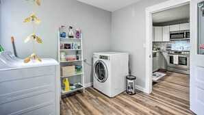 A laundry room with a washing machine, dryer, and shelves with cleaning supplies. - Charming Fort Collins Home By Old Town & Csu! (Fort Collins)