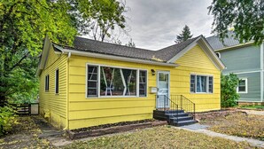 A yellow single-story house with a front porch, a small front yard, and a neighboring house. - Charming Fort Collins Home By Old Town & Csu! (Fort Collins)