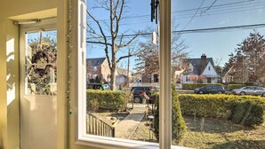 A room with a large window, a door, and a view of a residential street with houses and parked cars. - 5 Mi to National Mall: Home in Washington DC (Washington)