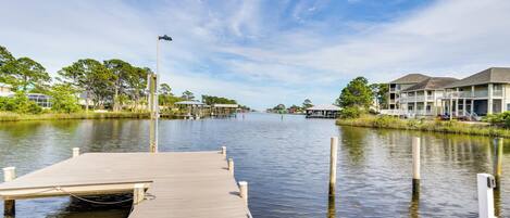 A wooden dock extending into calm water with a clear sky.