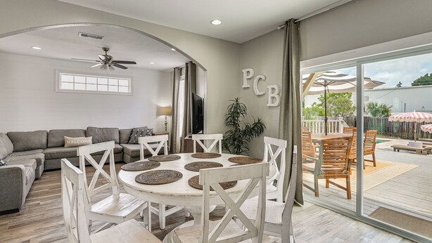 A spacious living area with a round table, white chairs, a grey sofa, and a ceiling fan. - 'bailey's Beach House Retreat' w/ Game Room! (Panama City Beach)