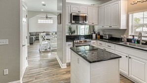 A modern kitchen with white cabinetry, a central island, a microwave, and a stove. - 'bailey's Beach House Retreat' w/ Game Room! (Panama City Beach)